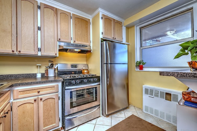 kitchen with light tile patterned floors, under cabinet range hood, appliances with stainless steel finishes, radiator heating unit, and dark countertops