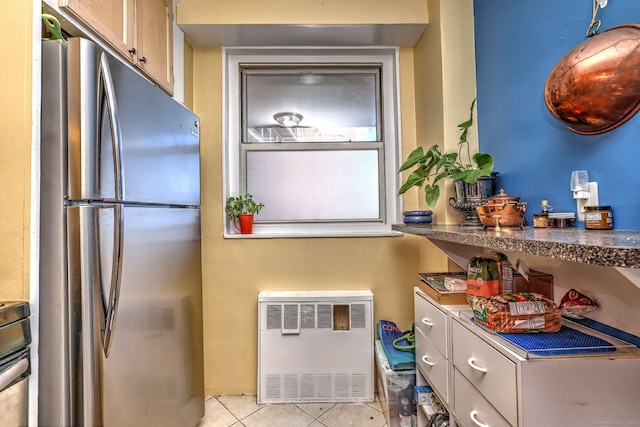 kitchen featuring freestanding refrigerator, heating unit, and light tile patterned floors