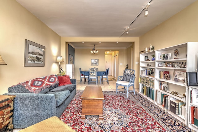 tiled living area with rail lighting, crown molding, and a notable chandelier