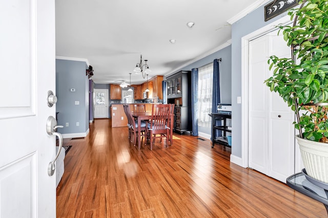 dining space with ornamental molding, light wood-style flooring, and baseboards