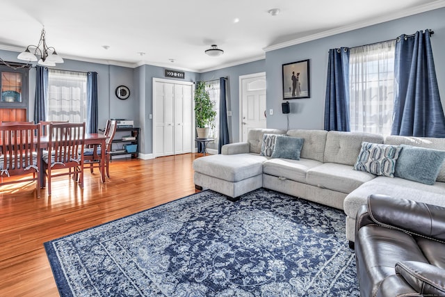 living area with a chandelier, ornamental molding, wood finished floors, and baseboards