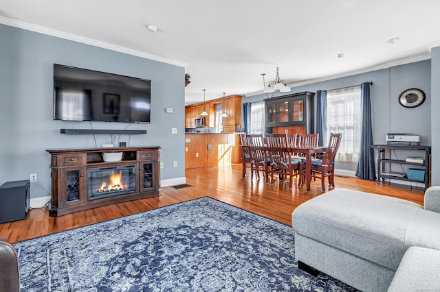 living room featuring ornamental molding, a glass covered fireplace, and wood finished floors