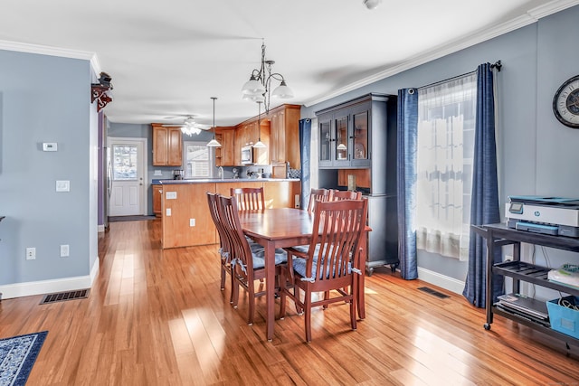 dining space with ornamental molding, light wood-style flooring, and visible vents