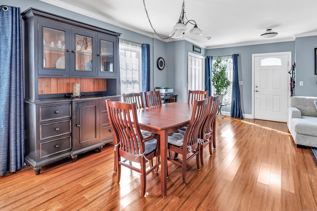 dining area with ornamental molding, light wood-style flooring, and baseboards