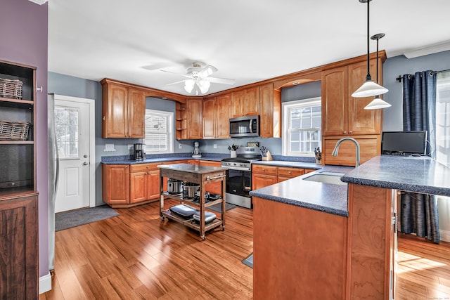 kitchen featuring open shelves, dark countertops, appliances with stainless steel finishes, a sink, and a peninsula