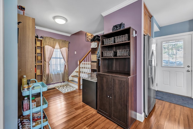 foyer entrance featuring light wood-style flooring, crown molding, stairway, and a wealth of natural light