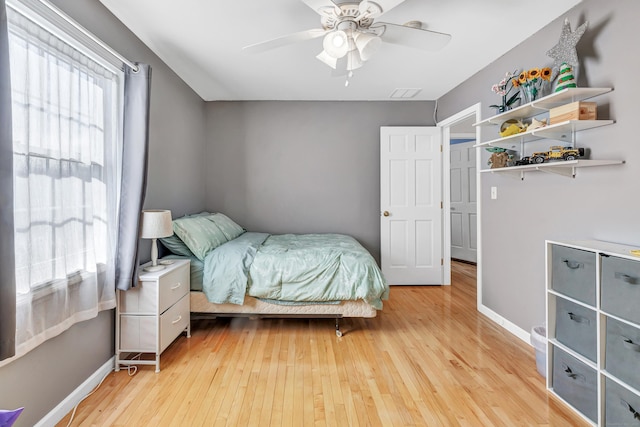 bedroom featuring light wood-type flooring, visible vents, ceiling fan, and baseboards