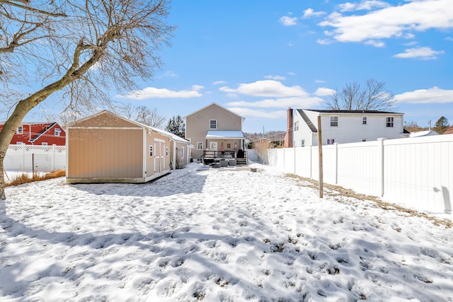 yard covered in snow featuring an outbuilding, a storage shed, and fence private yard