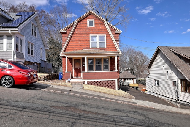 dutch colonial with solar panels, aphalt driveway, a gambrel roof, a porch, and central AC unit