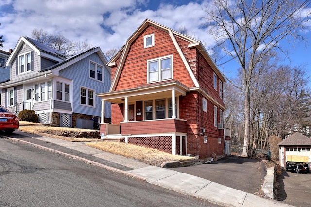 dutch colonial featuring covered porch, a gambrel roof, and driveway