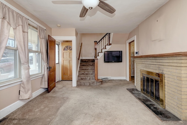 unfurnished living room featuring stairway, baseboards, a fireplace, ceiling fan, and carpet flooring