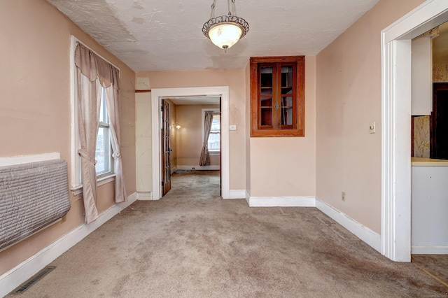 spare room featuring visible vents, a textured ceiling, baseboards, and carpet floors