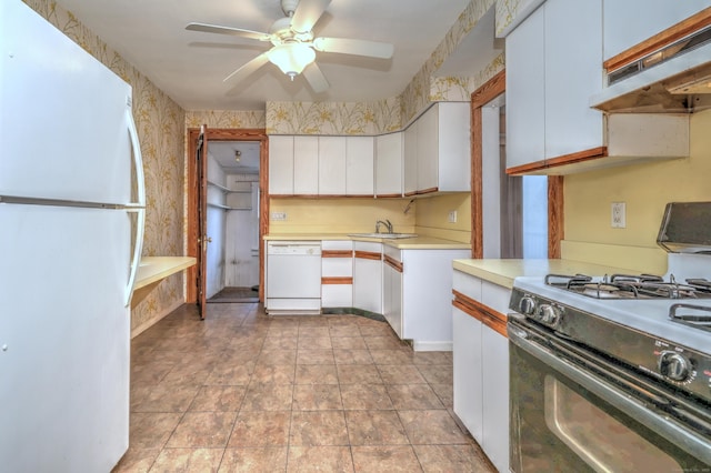 kitchen with under cabinet range hood, white cabinets, white appliances, and wallpapered walls