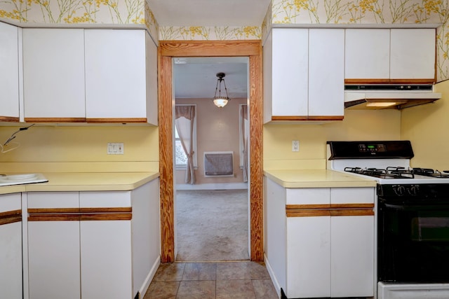 kitchen with under cabinet range hood, range with gas stovetop, white cabinetry, light countertops, and light colored carpet