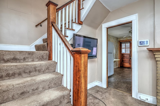 stairs with carpet, a ceiling fan, and baseboards