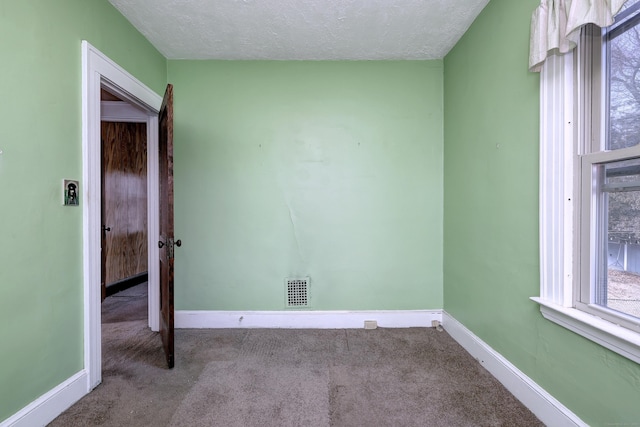 empty room with visible vents, baseboards, carpet, and a textured ceiling