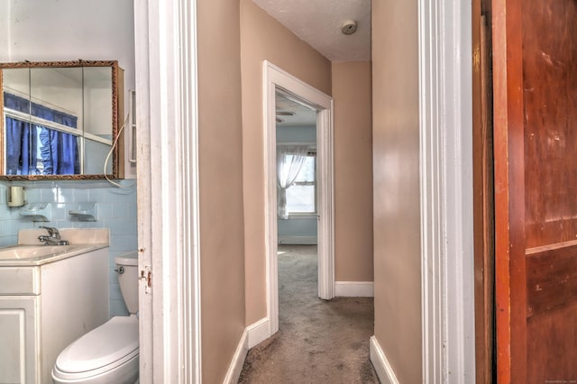 half bathroom with a textured ceiling, toilet, vanity, and baseboards