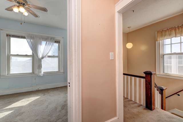 hallway featuring an upstairs landing, carpet, and baseboards