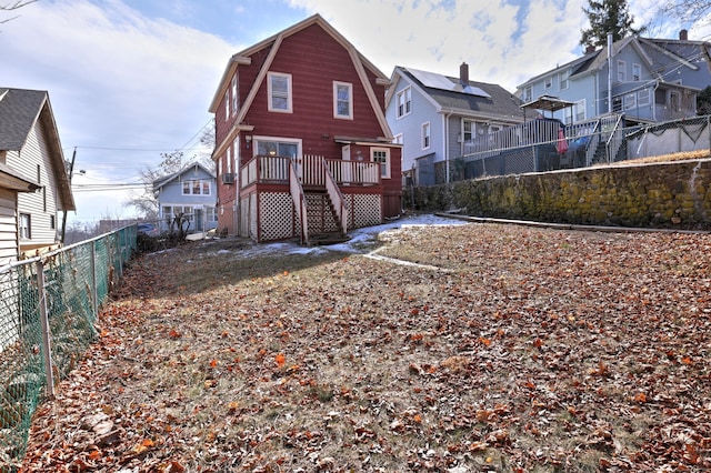 back of property with a residential view, a gambrel roof, a fenced backyard, and a deck