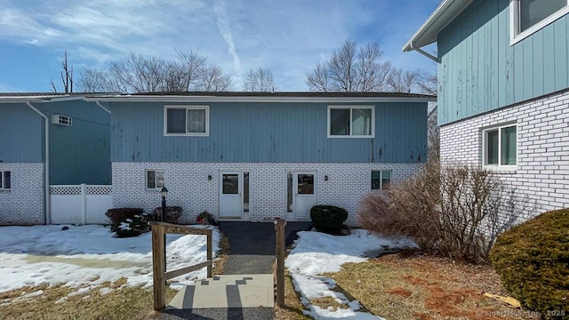 snow covered property featuring brick siding