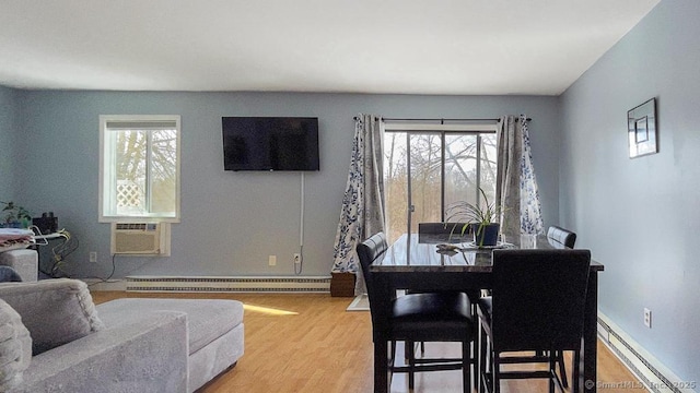 dining room featuring a wealth of natural light, a baseboard radiator, light wood finished floors, and baseboard heating