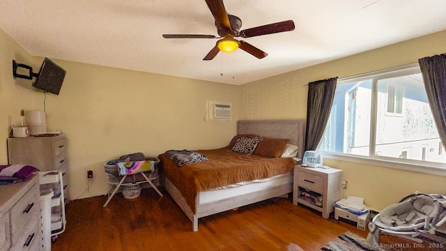 bedroom with a wall mounted AC, wood finished floors, and a ceiling fan