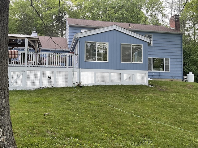view of side of property with a chimney, a yard, and a deck