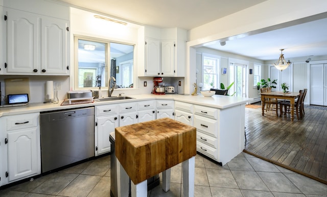 kitchen with a sink, a peninsula, white cabinets, and dishwasher