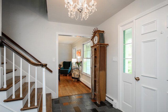 foyer with plenty of natural light, stairway, baseboard heating, and a notable chandelier