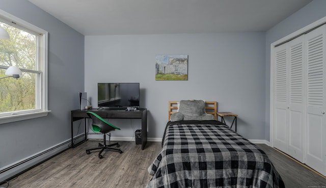 bedroom featuring baseboards, baseboard heating, a closet, and wood finished floors