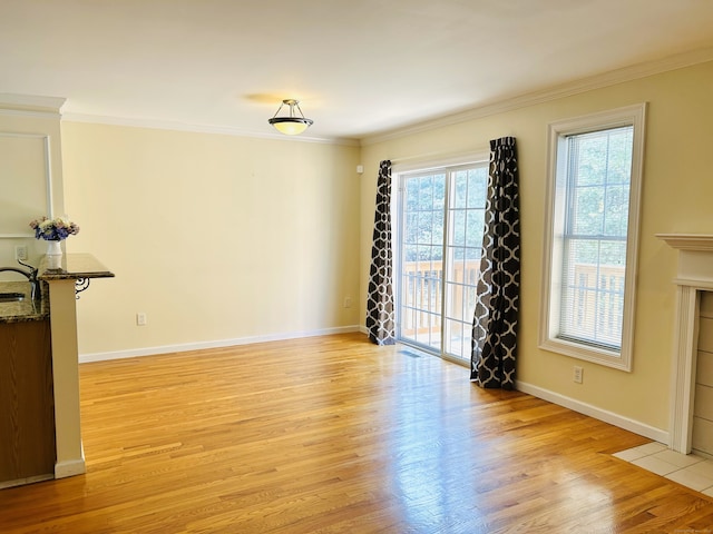 empty room featuring light wood-style flooring, baseboards, and ornamental molding