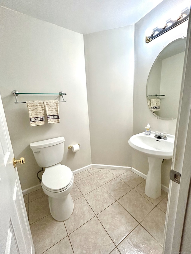 bathroom featuring tile patterned flooring, toilet, and baseboards