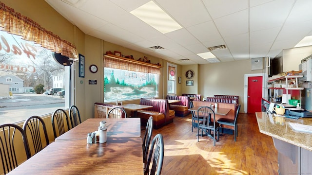 dining area featuring a drop ceiling, wood finished floors, and visible vents