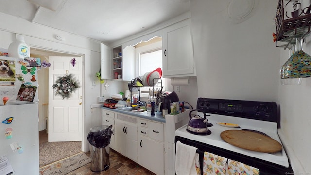 kitchen featuring a sink, white cabinetry, electric stove, freestanding refrigerator, and open shelves