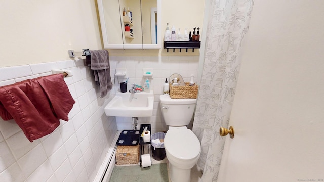 bathroom featuring a wainscoted wall, a sink, tile walls, and toilet