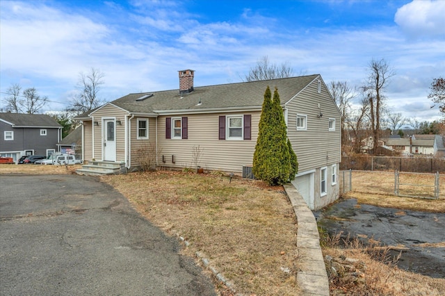 view of front of property featuring aphalt driveway, fence, a chimney, and an attached garage