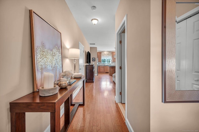 corridor with light wood finished floors and visible vents