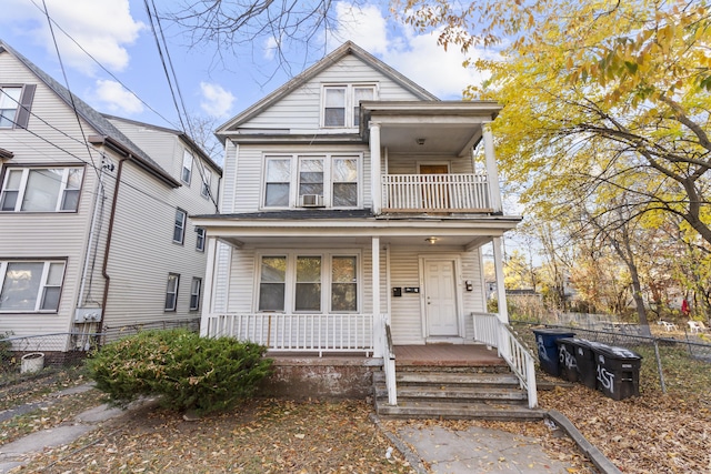 view of front of home with covered porch, fence, and a balcony