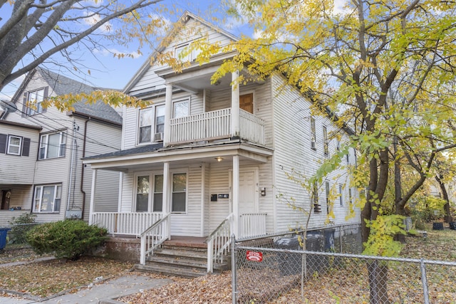 view of front of property featuring covered porch, fence, and a balcony