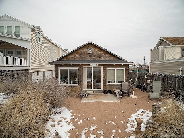 rear view of house featuring entry steps and fence