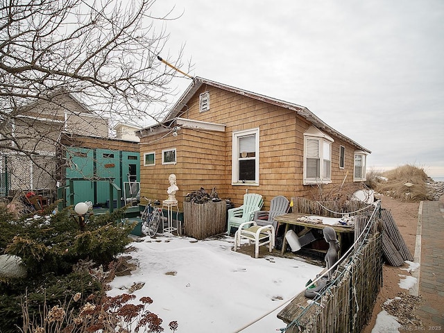 rear view of property featuring an outdoor structure and fence