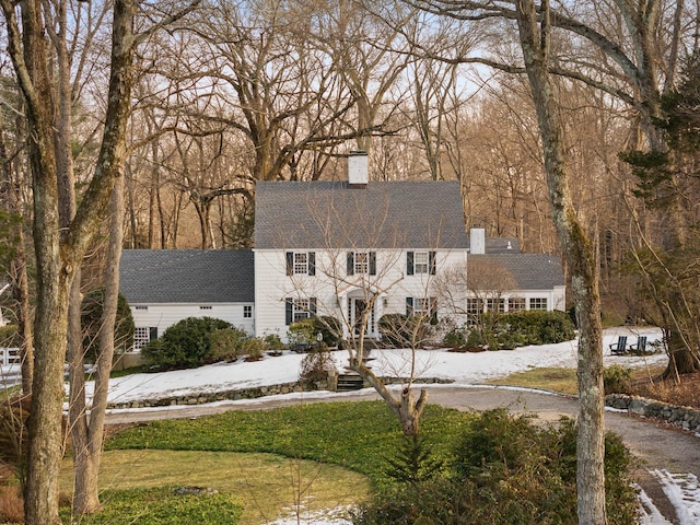 colonial-style house featuring a front yard and a chimney