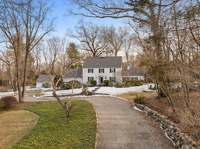 view of front of house featuring aphalt driveway, a front yard, and a chimney