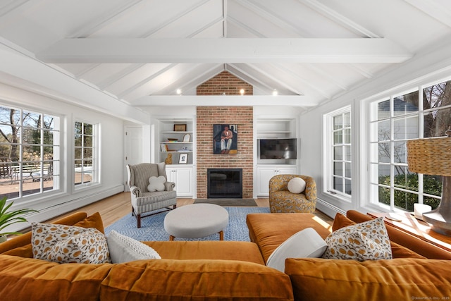 sunroom with a brick fireplace, a healthy amount of sunlight, and vaulted ceiling with beams