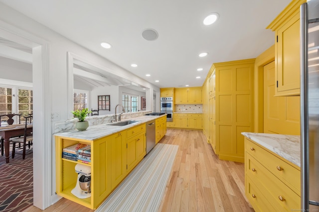 kitchen featuring light wood-style flooring, a sink, stainless steel appliances, backsplash, and recessed lighting