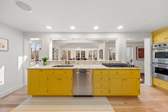 kitchen with appliances with stainless steel finishes, light wood-type flooring, a sink, and green cabinets