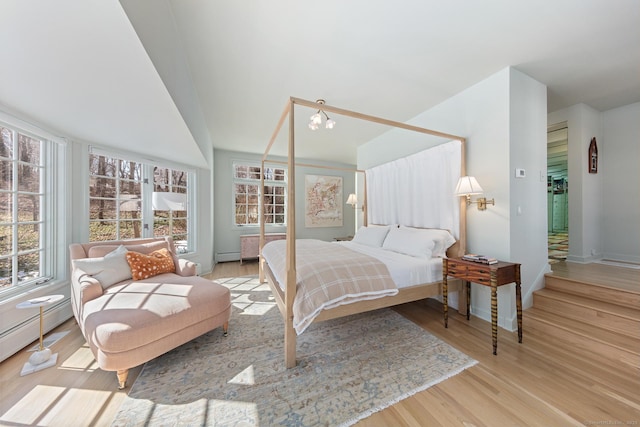 bedroom with baseboards, a baseboard radiator, wood finished floors, baseboard heating, and a chandelier