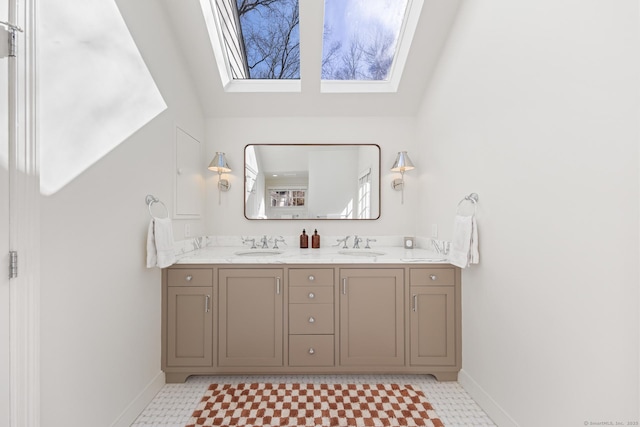 bathroom featuring a skylight, baseboards, and a sink