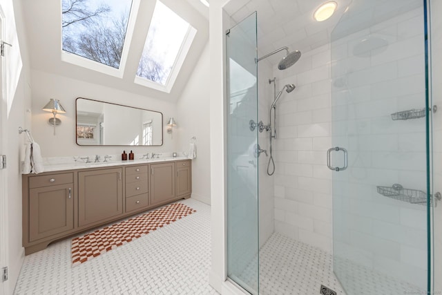 bathroom with vaulted ceiling with skylight, a sink, a shower stall, and double vanity