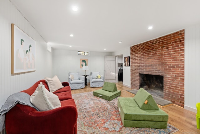 living area featuring recessed lighting, a brick fireplace, and light wood-style floors